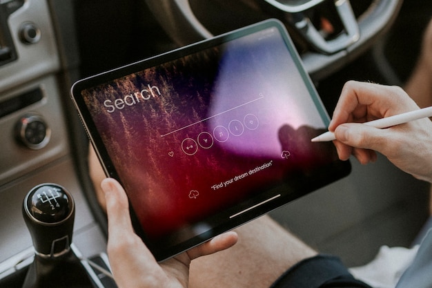 Mão segurando uma caneta stylus pesquisando em um tablet em um carro