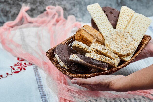 Mão segurando uma cesta de biscoitos mistos.