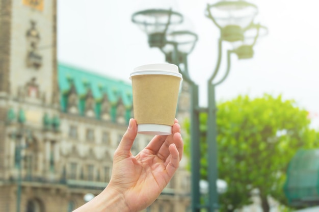 Mão segurando uma xícara de café para viagem