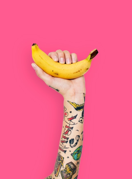 Mão tatuada segurando uma banana