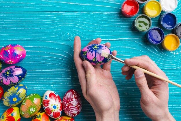 Mãos com pincel pintando um ovo de páscoa