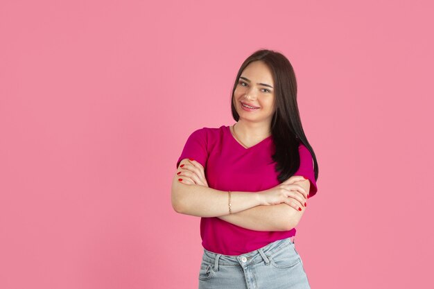 Mãos cruzadas. Retrato monocromático de jovem morena caucasiana, isolada na parede rosa.