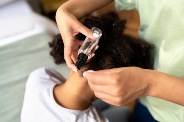 Mãos de alto ângulo aplicando tratamento contra piolhos