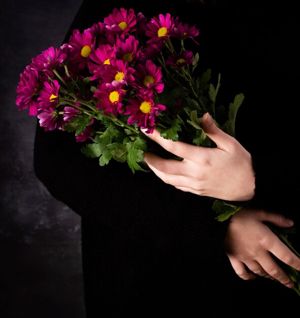 Mãos de alto ângulo com buquê de flores