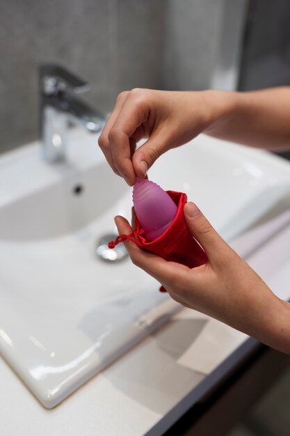 Mãos de alto ângulo segurando o copo menstrual