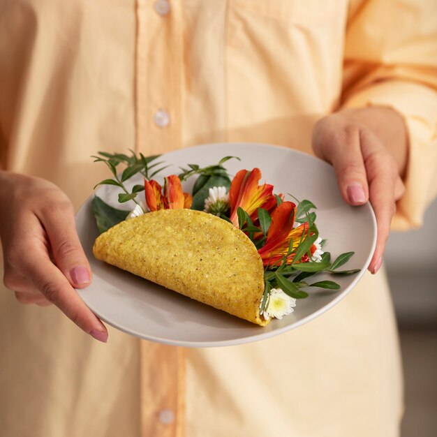 Foto grátis mãos de alto ângulo segurando prato com taco