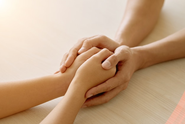 Mãos de amigo de apoio anônimo, segurando as mãos de mulher