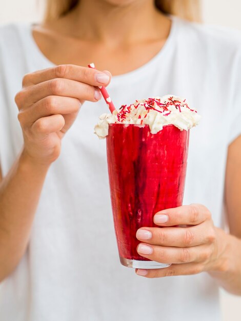 Mãos de close-up, segurando o copo vermelho milkshake