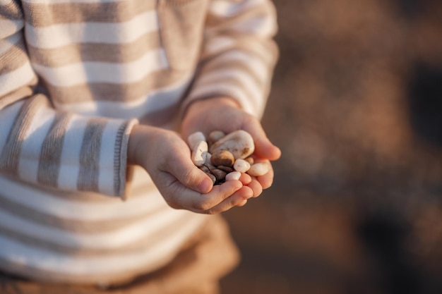 Mãos de criança com pedras perto do mar