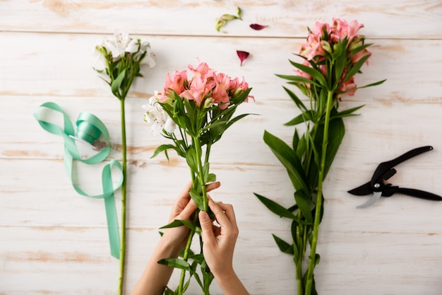 Mãos de florista vista superior fazendo buquê de flores