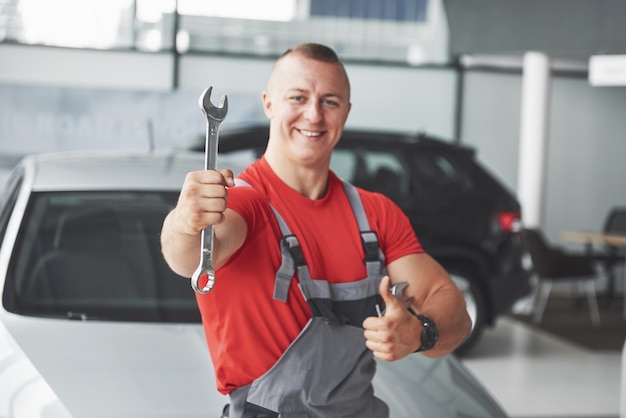 Mãos de mecânico de automóveis com uma chave inglesa na garagem.