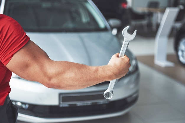 Mãos de mecânico de automóveis com uma chave inglesa na garagem.