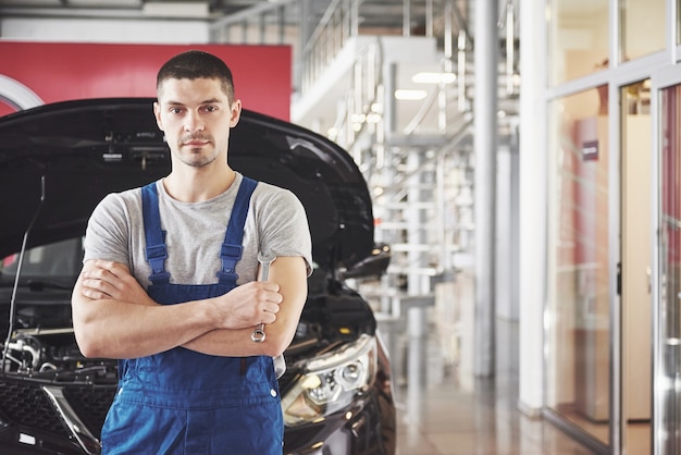 Mãos de mecânico de automóveis com uma chave inglesa na garagem.