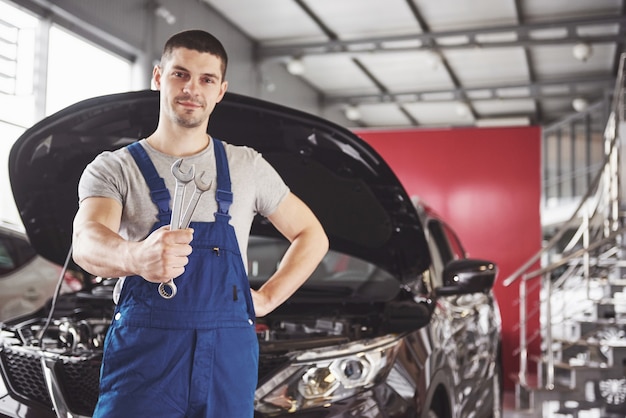 Mãos de mecânico de automóveis com uma chave inglesa na garagem.