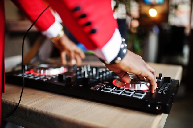 Mãos de moda homem afro-americano modelo DJ em terno vermelho com controlador de dj