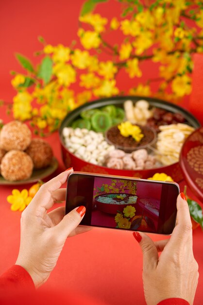 Mãos de mulher cortada fotografando comida tradicional na sua câmera do smartphone