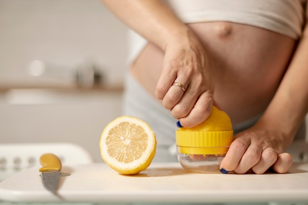 Mãos de mulher grávida fazendo limonada
