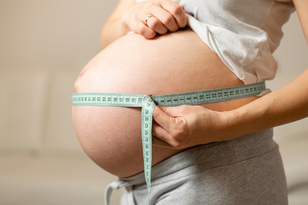 Mãos de mulher grávida medindo a barriga dela