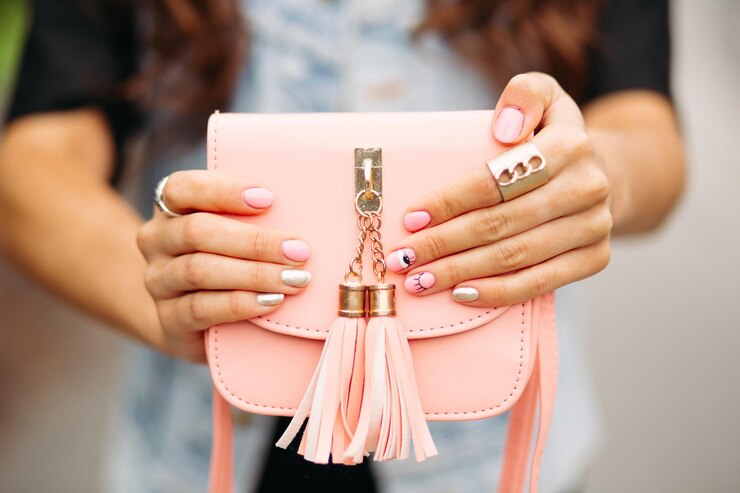 Foto grátis mãos de mulheres bonitas com manicure na moda segurando uma linda bolsa transversal de pêssego.