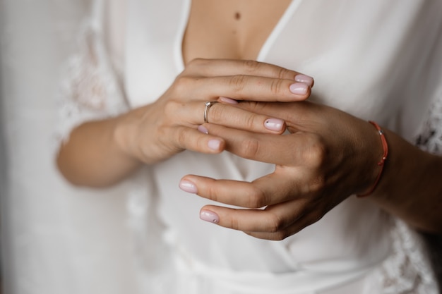 Mãos de uma noiva com um anel de noivado com diamante e uma manicure