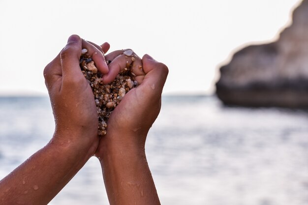 Mãos de uma pessoa negra agarrando pedras em forma de coração