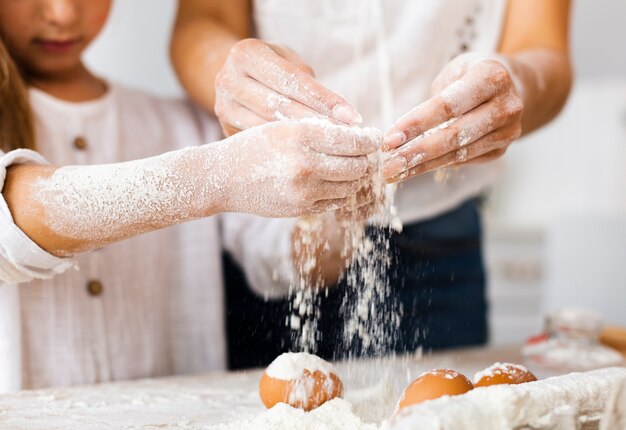 Mãos derramando farinha sobre ovos