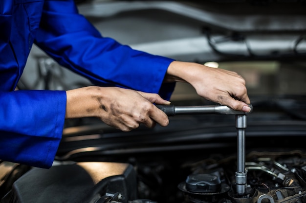 Mãos do mecânico fêmea atendendo um carro