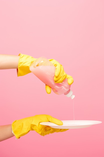 Foto grátis mãos em luvas de proteção amarelas, lavar um prato