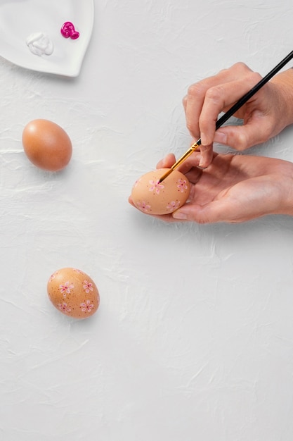 Mãos erguidas com pincel pintando ovos de páscoa