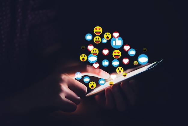 Mãos estão jogando interações de mídia social em telefones celulares em salas escuras. vários símbolos e opiniões são aceitos. conceito de mídia social.