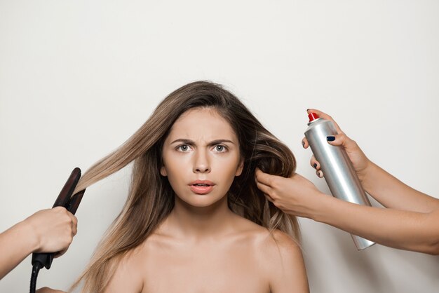 Mãos fazendo penteado para jovem mulher bonita