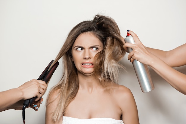 Mãos fazendo penteado para jovem mulher bonita