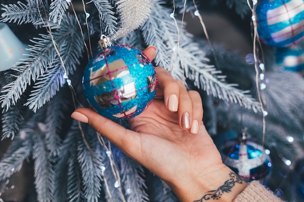 Mãos femininas com design de unhas de Natal de ano novo. Manicure com esmalte bege nu, um dedo bronze dourado brilhante