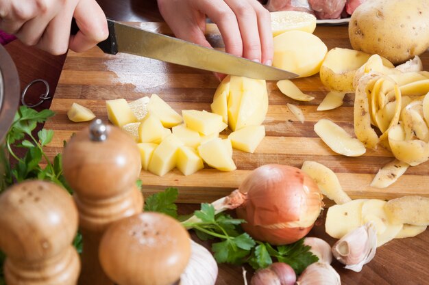 mãos femininas cortando batatas