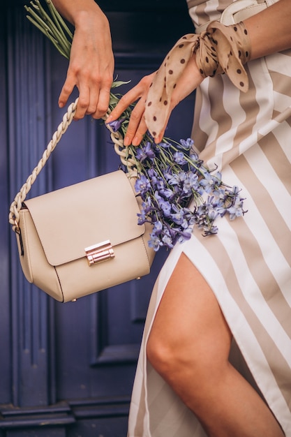 Foto grátis mãos femininas fecham segurando uma bolsa e flores