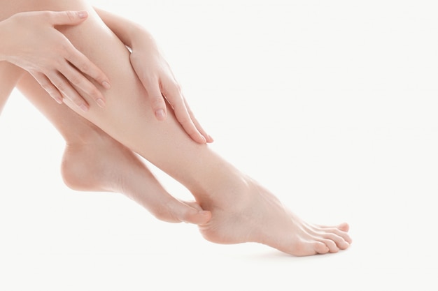 mãos femininas sobre as pernas, conceito de cuidados do corpo de pele