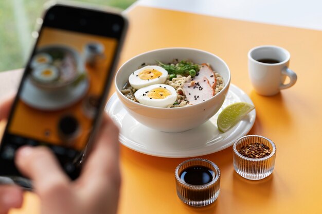 Mãos femininas tirando foto de uma tigela de ramen