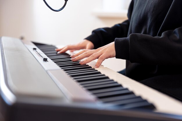 Mãos femininas tocam teclas musicais com foco suave