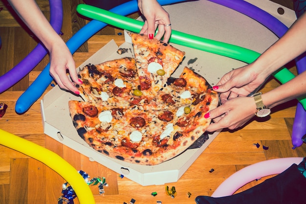 Mãos levando fatias de pizza