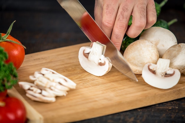 Mãos masculinas cortando vegetais para salada