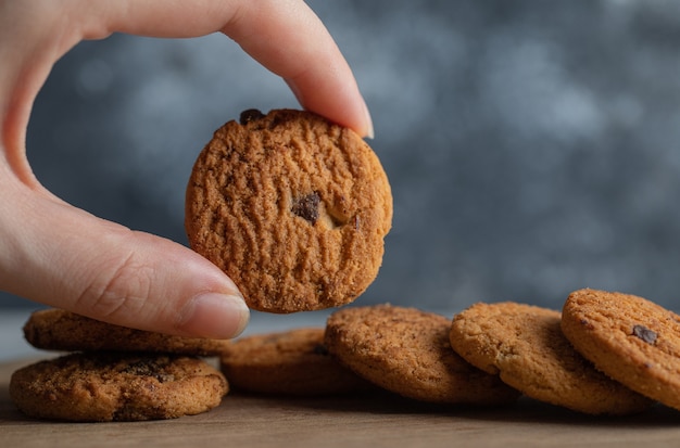 Mãos masculinas segurando deliciosos biscoitos de chocolate no fundo de mármore