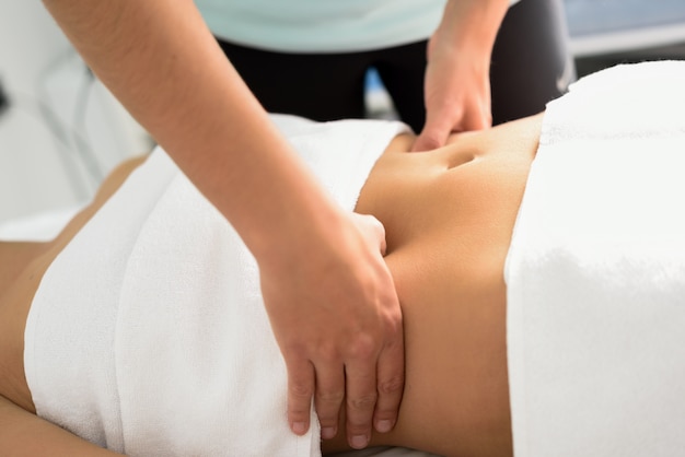 Mãos massageando o abdômen feminino.Therapista aplicando pressão sobre a barriga.