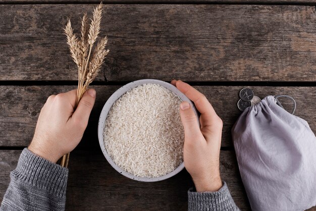 Mãos planas leigas segurando uma tigela com arroz