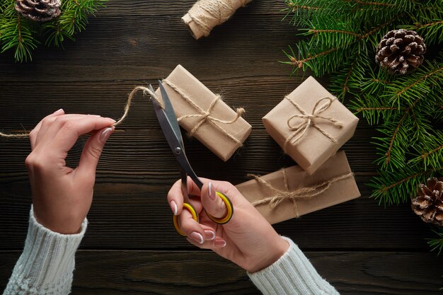 Mãos que cortam o cordão de um pacote de presente