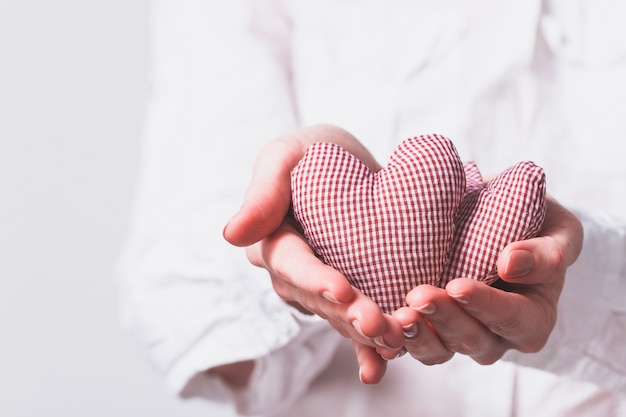 Mãos que prendem dois corações de pelúcia