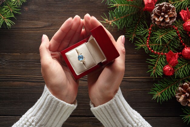 Mãos que prendem uma caixa com um anel com uma pedra azul