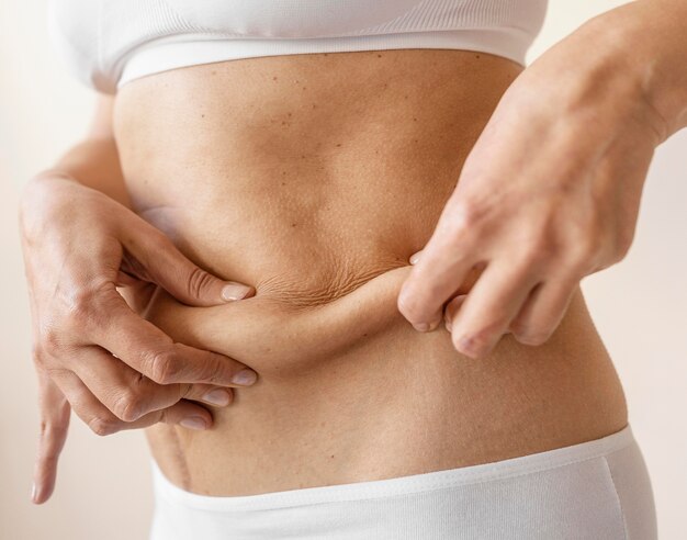 Mãos segurando a barriga de perto