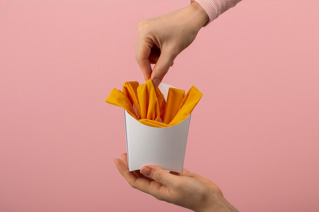 Foto grátis mãos segurando batatas fritas feitas de roupas