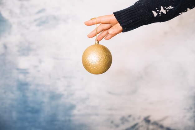 Mãos segurando bola de Natal elegante