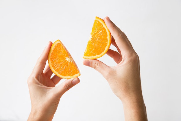 Foto grátis mãos segurando cortadas seções laranja